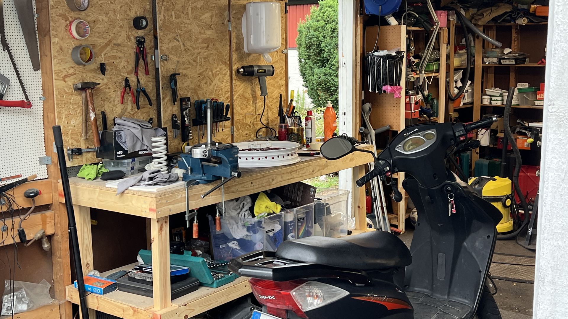 Arbetsbänk med skruvstäd och en scooter i verkstaden